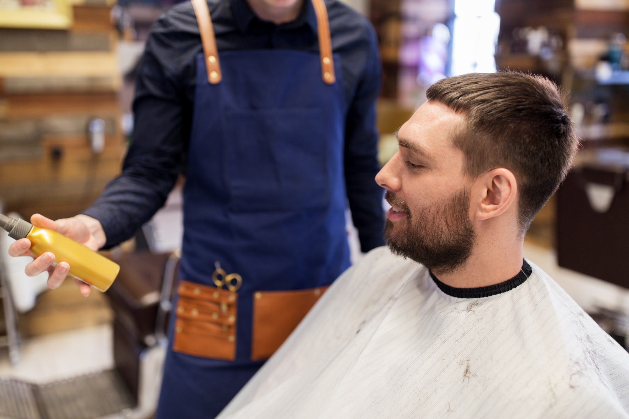 barber showing hair styling spray to male customer