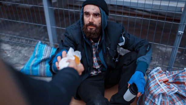 Male person gives food to bearded dirty beggar